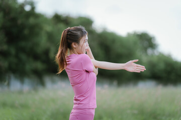 
A young woman in pink athletic wear pauses, seemingly catching her breath after exercise, looking...