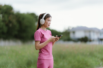 
A young woman in pink athletic wear pauses, seemingly catching her breath after exercise, looking...