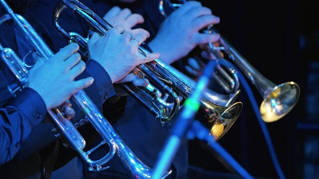 Close-up of several musicians playing trumpets in an orchestra, demonstrating their skill and passion. The trumpet section of a big band