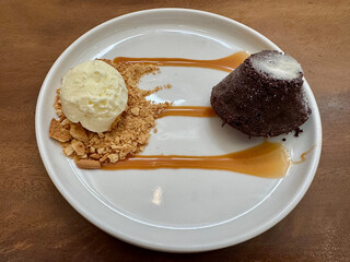 A chocolate Lava Cake menu served on a white plate with a scoop of vanilla ice cream, cake...