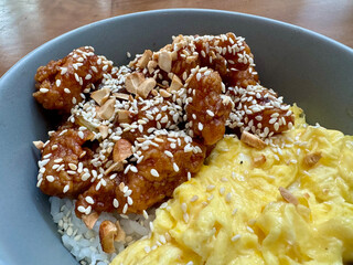 A bowl of rice with scrambled egg, chicken cubes and sesame seed