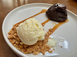 A chocolate Lava Cake menu served on a white plate with a scoop of vanilla ice cream, cake crumbles, and caramel sauce