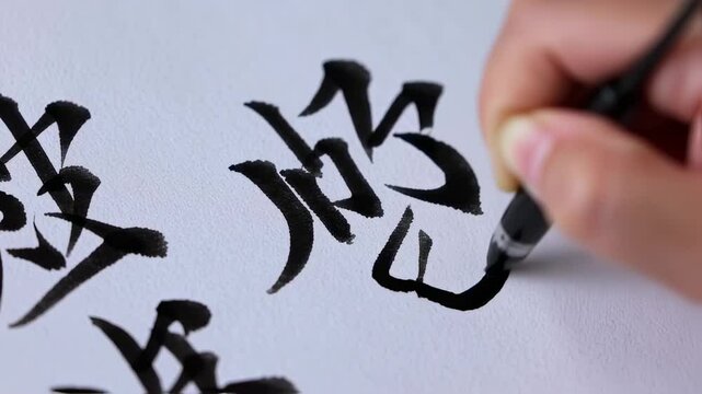 Detailed calligraphy demonstration capturing a hand gracefully writing Asian symbols