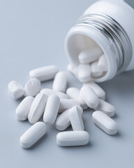 Close-up of white calcium tablets spilled from bottle onto clean white background, clear and simple for supplement ads or pharmacy visuals 