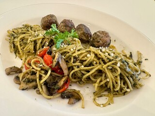 A delicious Pesto spaghetti with meatballs, mushroom, and tomato slices