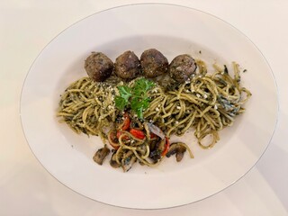 A delicious Pesto spaghetti with meatballs, mushroom, and tomato slices