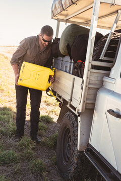 Man filling his four wheel drive with diesel from a jerry can