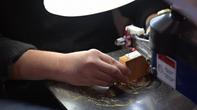 Scroll saw, making wooden timber child toy, cutting shape in wood with band saw in workshop	