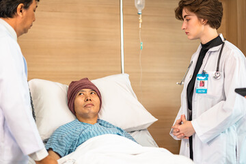 Asian man cancer patient visiting young female doctor for medical consultation in clinic. male patient struggling with cancer, healthcare. Medicine concept.Female doctor explaining xray to patient.