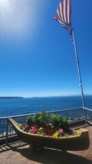 Wooden boat structure planter with beautiful flowers and flagpole with american flag with view of...