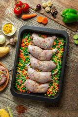 Raw stuffed chicken thigh, chicken casserole with vegetables, top view.