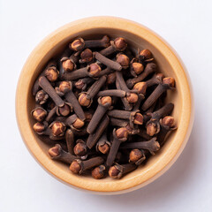 Obraz premium Top view of cloves in small wooden bowl on white surface, bright lighting, perfect for recipe blogs, herbal product displays, or kitchen-themed ads