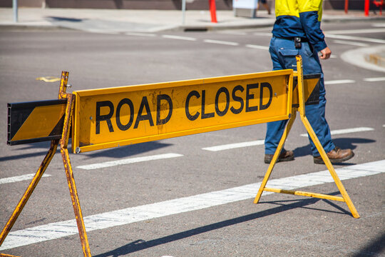 Council worker walking past road closed sign
