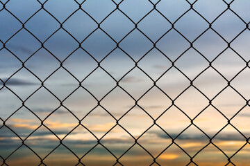 Fototapeta premium Old metal wire fence rust on the evening sky background.