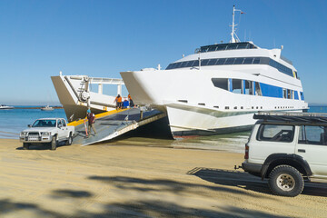 4WD's driving off a car ferry onto a beach