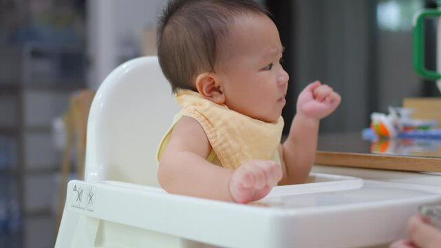 8 month old baby learning to eat for the first time. The concept of a child who has difficulty eating, playing while eating.