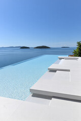 Fototapeta premium Stunning infinity pool overlooking tranquil sea and distant islands in clear weather