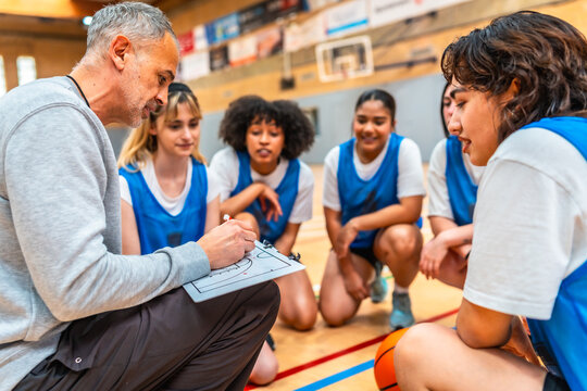 Basketball coach explaining strategy to female team