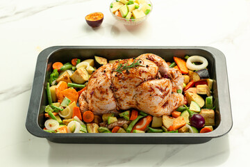 Whole raw stuffed and marinated chicken ready for oven with vegetables, white background.