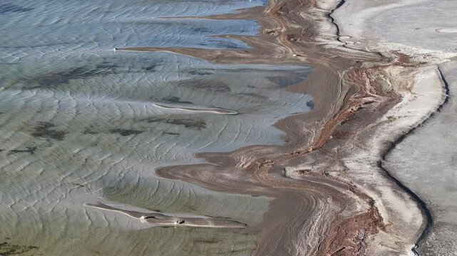 Aerial Great Salt Lake mud shore environment overhead 2. Largest saltwater lake in the Western Hemisphere. Solar evaporation ponds produce salt, potassium, magnesium. Recreation and industry.
