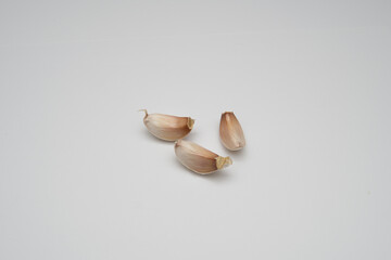 Photographic close-up of three garlic cloves on a white background for food blogs recipe websites and culinary applications minimalist food photography style