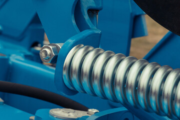 Silver hard spring made of steel. Part of big blue industrial or agricultural machine