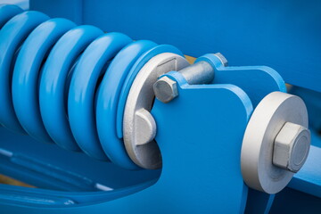 Blue hard spring made of steel. Part of big industrial or agricultural machine