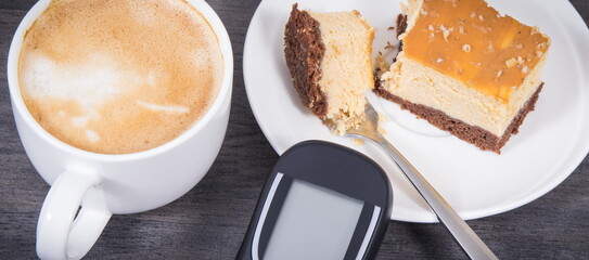 Glucometer, sweet cheesecake and cup of coffee with milk. Measuring and sugar level control during diabetes
