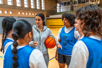 Female basketball coach explaining game strategy to team in gymnasium