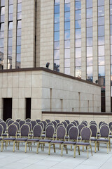 Chairs arranged in rows for a formal event against a backdrop of modern architecture.