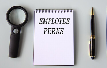 EMPLOYEE PERKS - words on a black notebook with a magnifying glass and pen in the background