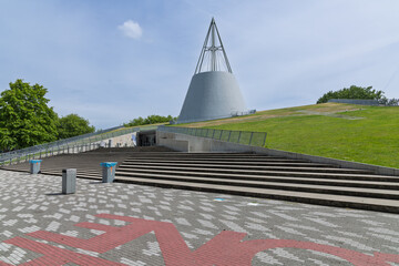 The iconic TU Delft Library building, featuring a distinctive conical roof and a sloping green roof, a landmark of modern architecture.