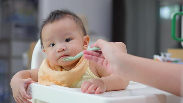 8 month old baby learning to eat for the first time. The concept of a child who has difficulty eating, playing while eating.
