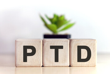 PTD concept on wooden cubes and flower in a pot in the background