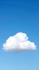 A fluffy white cloud drifts lazily across a bright blue sky, casting a soft shadow on the landscape below, creating a serene and tranquil atmosphere.