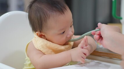 8 month old baby learning to eat for the first time. The concept of a child who has difficulty eating, playing while eating.