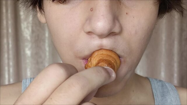 A teenage boy bites off a cookie and chews. Close-up chewing. Carbohydrates in the diet.