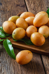 Fresh Yellow Fruits on Wooden Table Surrounded by Green Leaves for Healthy Eating