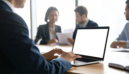 Business meeting with professionals discussing documents, person using laptop with blank screen, modern office environment, teamwork and collaboration, focused atmosphere