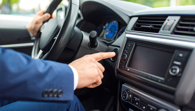Businessman hand pressing start button in modern car interior, ready to drive, showing technology and convenience in transportation