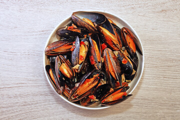 Mussels in garlic cream sauce on wooden table   