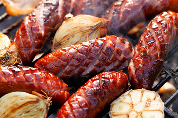 Grilled pork sausages with addition onion and garlic on a cast iron grill,  close up view