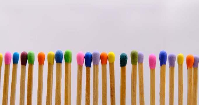 multicolored match sticks in rotation on a rotating table with white background, close up view, full screen