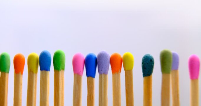 multicolored match sticks in rotation on a rotating table with white background, close up view, full screen