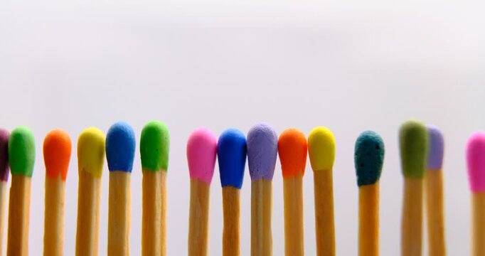 multicolored match sticks in rotation on a rotating table with white background, close up view, full screen