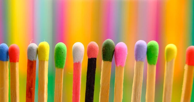 multicolored match sticks in rotation on a rotating table with wooden popsicles in background, close up view, full screen