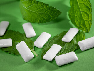 Chewing gums, white dragees on mint leaves, freshening breath, healthy teeth