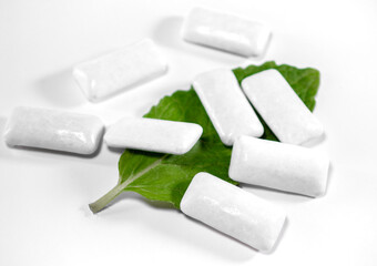 Refreshing chewing gums in dragees on a white background, mint leaf