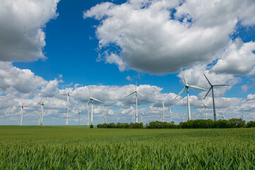 Modern wind turbines spinning over vibrant green fields in rural Germany. A powerful symbol of the Energiewende and Germany’s response to climate change and energy transition. green energy