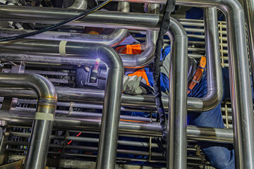 Male worker wearing protective clothing of repair pipe stainless argon welding industrial